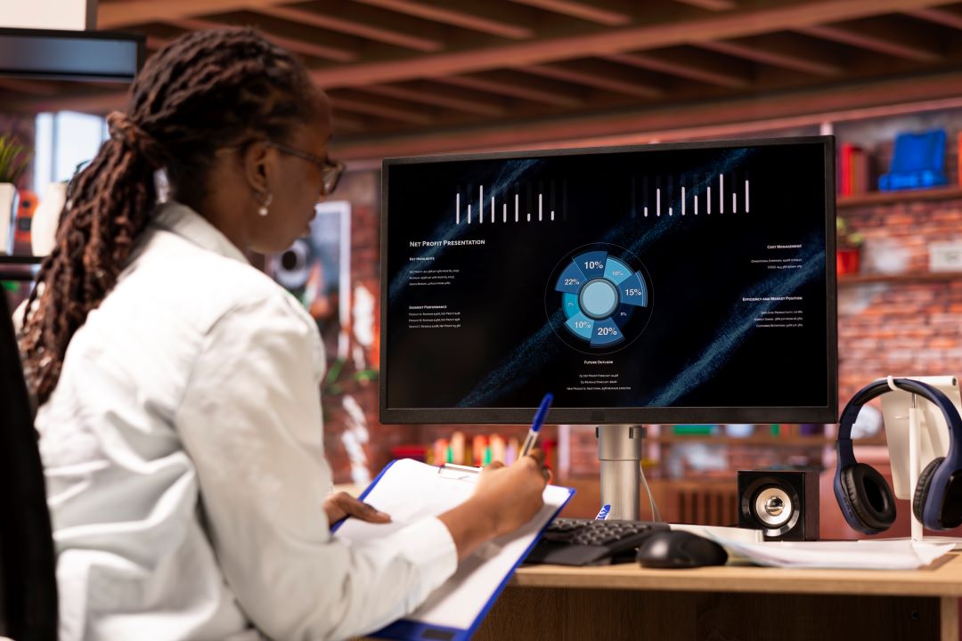 woman-looking-sales-statistics-computer-taking-notes